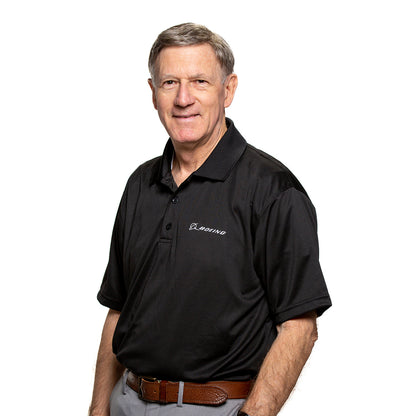 Male model wearing the Mesh tech polo in black color tucked in grey pants and brown belt.