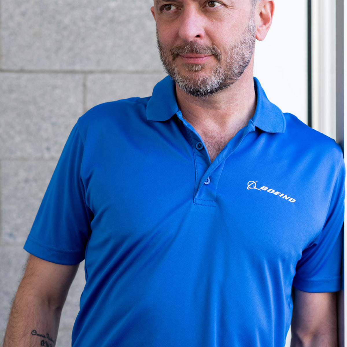 Close up of the polo in royal.  Model leaning against a wall.