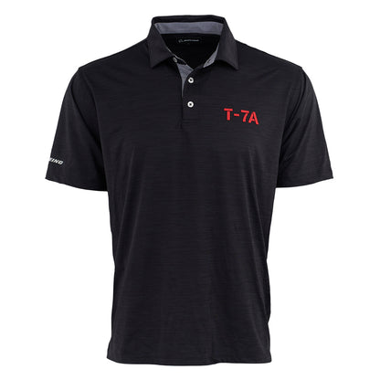 The Boeing T-7A Red Hawk Series Men’s Polo by BOEING is a black short-sleeve polo with a collar, three buttons, “T-7A” in red on the left chest, “Boeing” on the right sleeve, UPF 50 sun protection, and a subtle textured pattern.