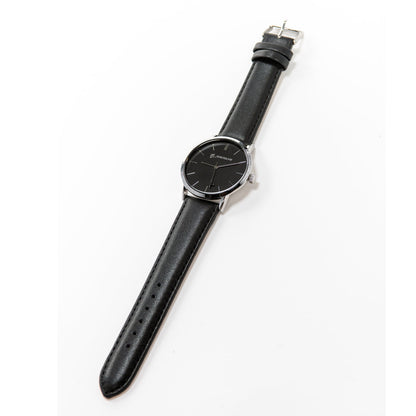 The Boeing Silver Rotating Airplane Watch showcases a sleek mens design with a black leather strap and watch face, featuring distinctive silver markers and hands reminiscent of Boeing precision. It rests elegantly against a plain white surface.