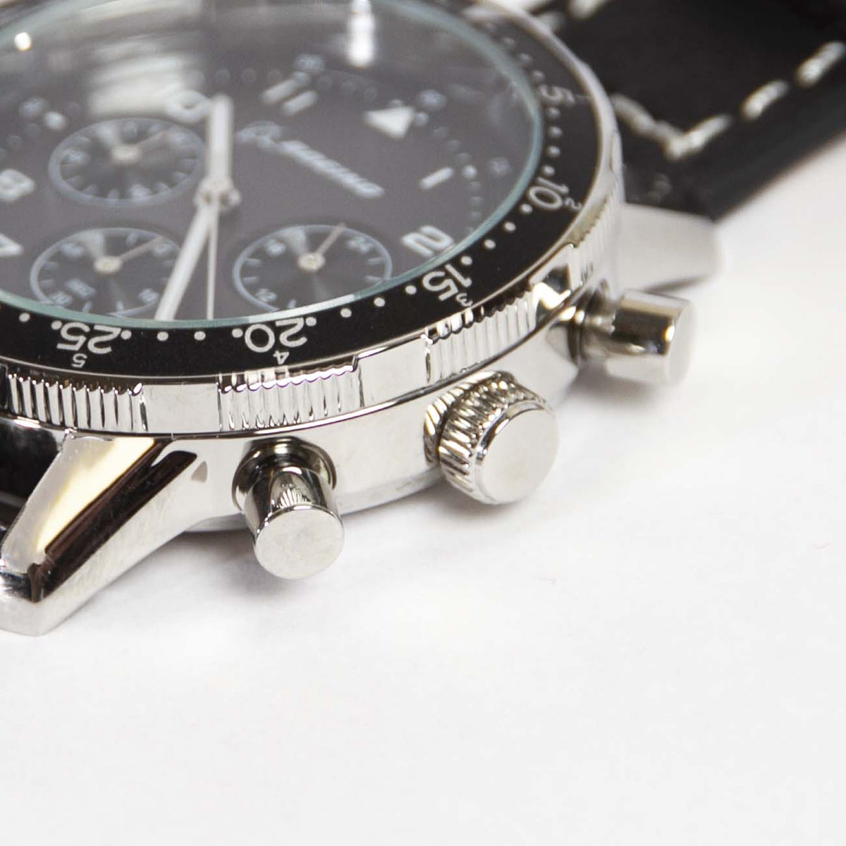 Close-up of the Boeing Black Leather Watch from The Boeing Store features a sleek black dial with silver markers and three subdials. A rotating bezel adds to its charm, while the side view reveals a 10 ATM water-resistant stainless steel case with a textured crown, push buttons, and black leather strap.