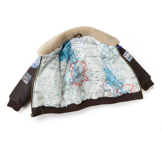 The Boeing Stores Boeing Kids Brown Aviator Jacket features a shearling-fleece collar, a vintage-style map lining with red markings, and aviation-themed patches and badges on the sleeves.