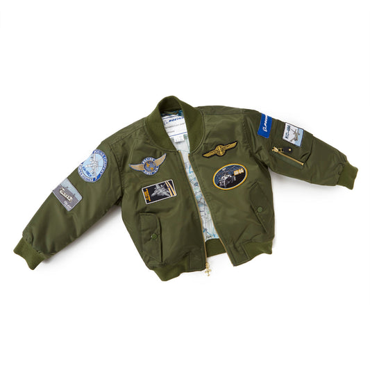 The Boeing Stores Boeing Kids Green Flight Jacket is a nylon bomber with aviation-themed patches and aircraft motifs on the front, sleeves, and shoulders. It features a light blue map design lining inside, perfect for young aviation fans.
