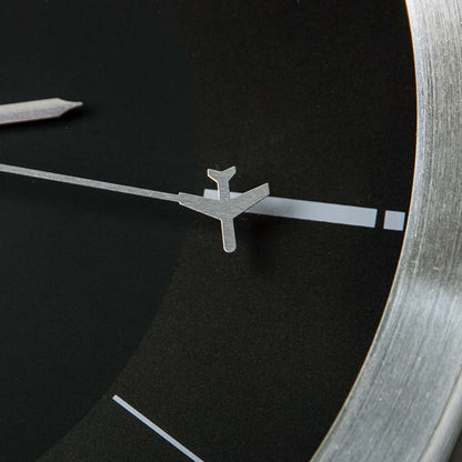 Close-up of the Boeing Rotating Plane Clock by The Boeing Store, a minimalist design featuring a black face, simple white hour markers, and a unique silver airplane-shaped second hand.