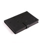 A Boeing CST-100 Starliner Notebook from The Boeing Store, featuring a black PU hardcover with raised geometric patterns and a matching strap closure, lies on a white surface. Its sleek design, resembling an aircraft stamp, includes subtle embossed details symbolizing Boeings precision.