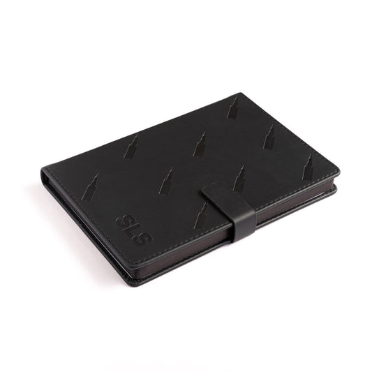The Boeing Stores Boeing SLS Notebook is a sleek, black leather notebook with a subtle embossed pattern and clasp closure. It features SLS in the corner and offers a stylish, professional look perfect for aviation enthusiasts and reminiscent of Boeings aircraft precision.