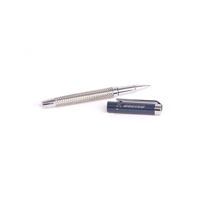 A sleek pen from The Boeing Stores Braided Steel Pen Set lies on a white background. The textured grip and cap, featuring the Boeing inscription, make it an elegant choice for any collection or sophisticated set.