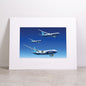 Introducing the Boeing 777X Family Matted Print - Small by Boeing: a high-resolution print featuring three Boeing airplanes in flight at varying angles, set against a clear blue sky. This striking artwork is presented in a white matted frame and features the iconic Boeing logo embossed at the bottom.