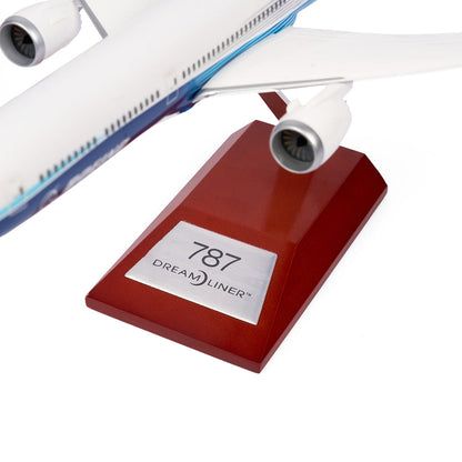 A close-up of the Boeing Unified 787-10 Dreamliner 1:200 Model by The Boeing Store showcases the engine and part of the wing on a wooden stand with a metallic plaque, emphasizing its sleek design as part of the 787 family.