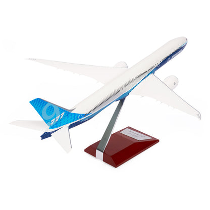 The Boeing Stores Boeing Unified 777-9 1:200 Model, featuring a white body with blue accents and a stylized tail design, is showcased on a sleek stand against a plain white background, delighting aviation enthusiasts and collectors of Boeing memorabilia.