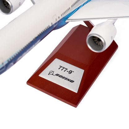 Close-up of The Boeing Stores Boeing Unified 777-9 1:200 Model airplane with two engines and a wing segment. It stands on a wooden base with a silver 777-9 plaque and the iconic Boeing logo, making it ideal memorabilia for aviation enthusiasts.