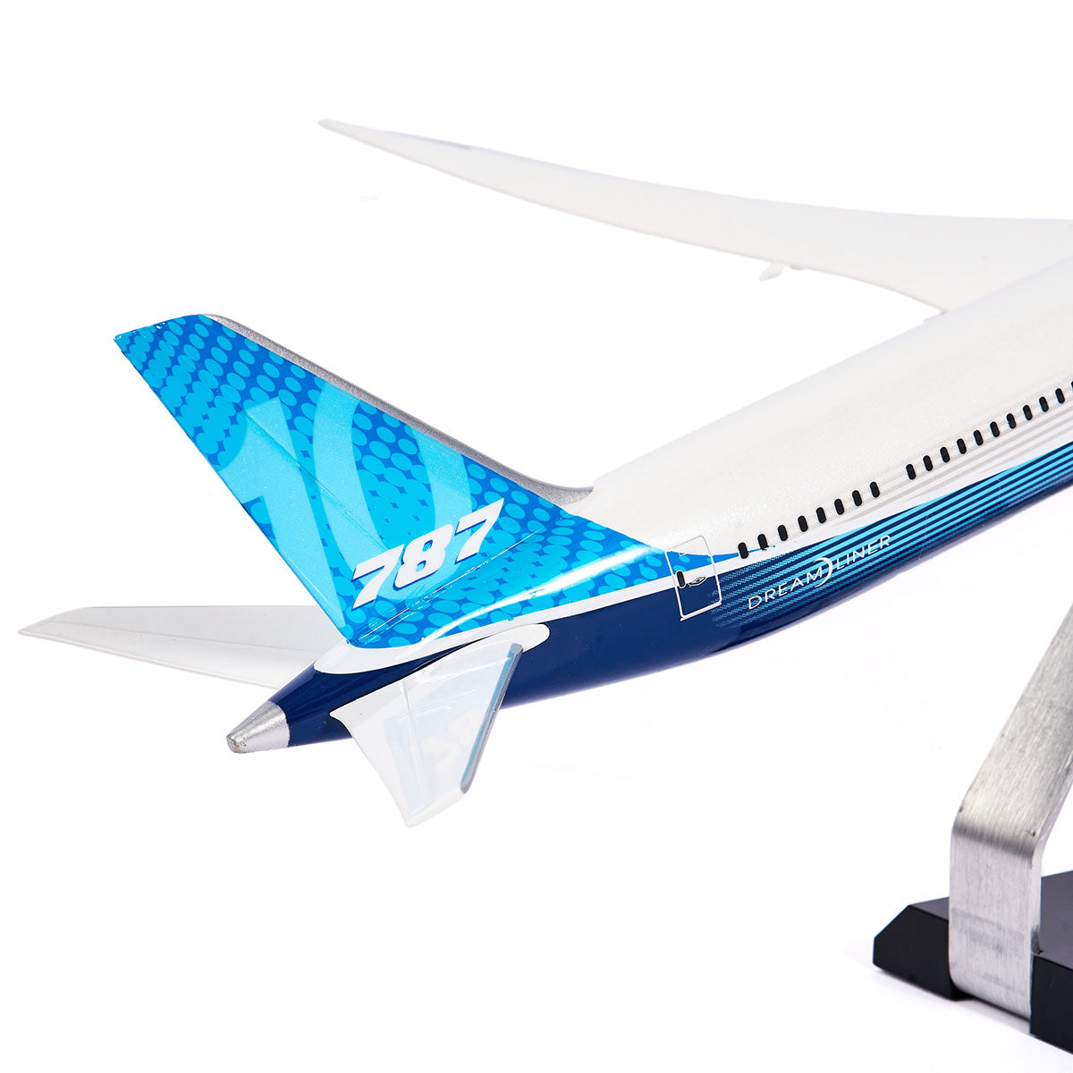 A close-up of the Pacific Miniatures Boeing Unified 787-10 Dreamliner Plastic 1:144 Model’s blue tail, showing the white 787 and Dreamliner logo, mounted on a metal stand against a white background.