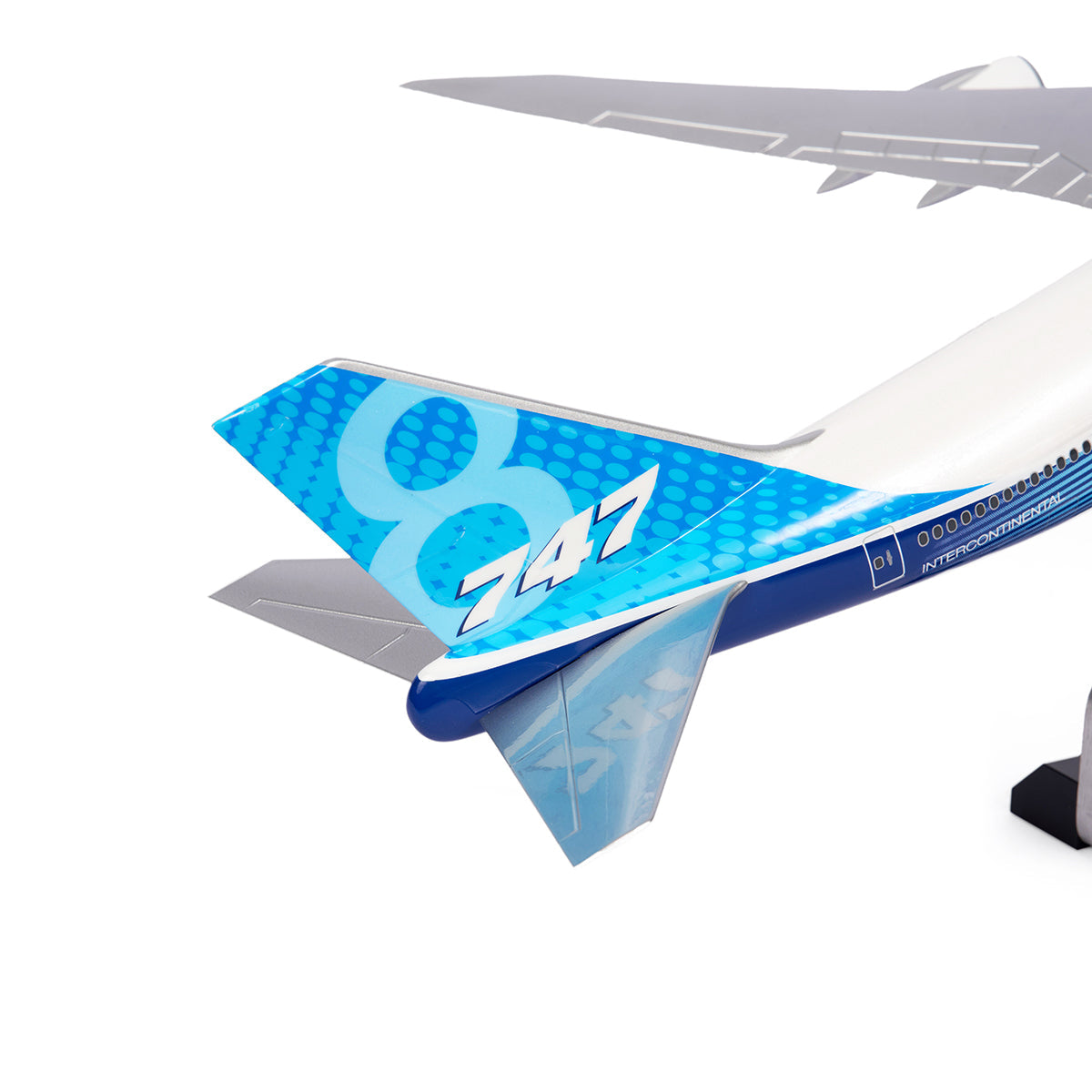 Close-up of The Boeing Store’s Boeing Unified 747-8i 1:144 Model tail, with 747-8 Intercontinental in white on blue and a modern dotted design. The premium model is partially supported by a stand against a white background.