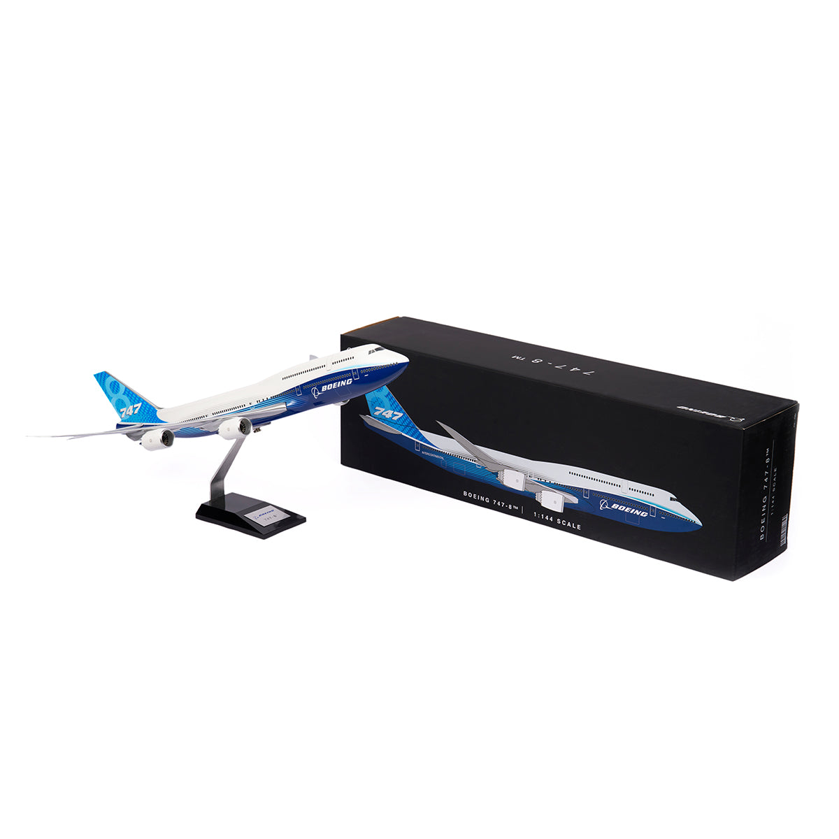 The Boeing Stores Boeing Unified 747-8i 1:144 Model, painted blue and white, is displayed on a black stand beside its black box packaging with an image of the plane and premium value branding.