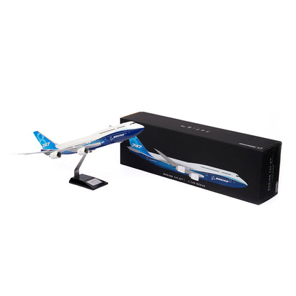 The Boeing Stores Boeing Unified 747-8i 1:144 Model, painted blue and white, is displayed on a black stand beside its black box packaging with an image of the plane and premium value branding.