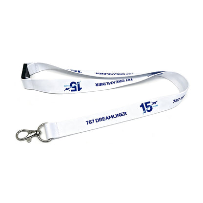 The BOEING 787 Dreamliner 15 Year Anniversary Lanyard is a white aviation lanyard featuring blue “787 DREAMLINER” and “15 YEARS” text alongside a BOEING logo. This pilot lanyard includes a metal clip and a black plastic buckle, and is shown on a white background.