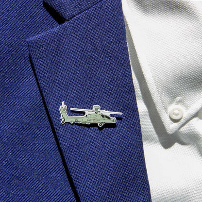 The Boeing Illustrated AH-64 Lapel Pin from The Boeing Store, featuring a silver-tone helicopter shape with an epoxy finish, adorns the blue textured suit lapel and complements the white shirt with visible buttons.