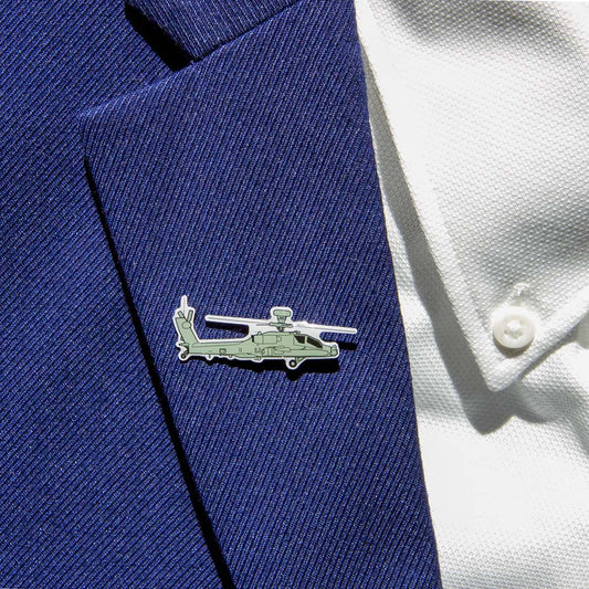 The Boeing Illustrated AH-64 Lapel Pin from The Boeing Store, featuring a silver-tone helicopter shape with an epoxy finish, adorns the blue textured suit lapel and complements the white shirt with visible buttons.