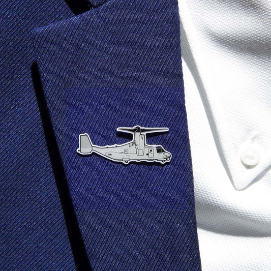 The Boeing Stores Boeing Illustrated V-22 Lapel Pin, in a silver tone with an aircraft outline and epoxy finish, adds elegance to the navy blue blazer lapel. It beautifully complements the white shirt beneath.