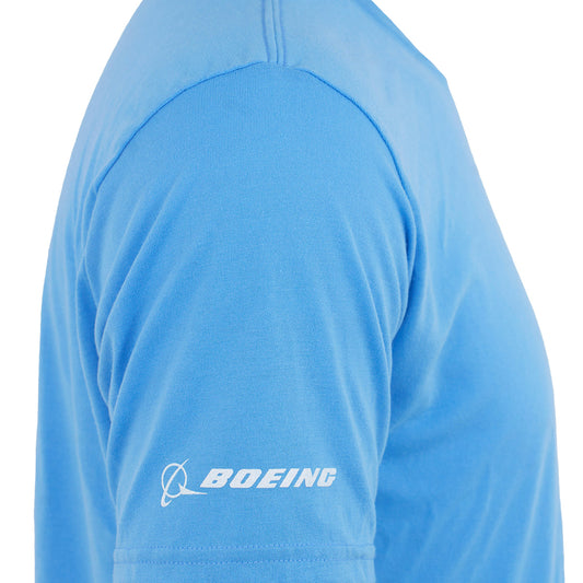 A close-up shows a person wearing the Boeing 777 Series Unisex T-Shirt in sky blue. The BOEING name and logo appear in white on the sleeve near the edge, making it an ideal pick for aviation fans. The focus is on the upper arm and shoulder.