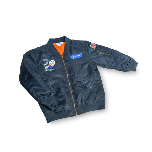 The Boeing Stores Boeing Kids Space Jacket is a dark bomber with space-themed patches, including an American flag on the right sleeve, and a Boeing logo. Its water-resistant with a bright orange lining and front zipper for added flair.