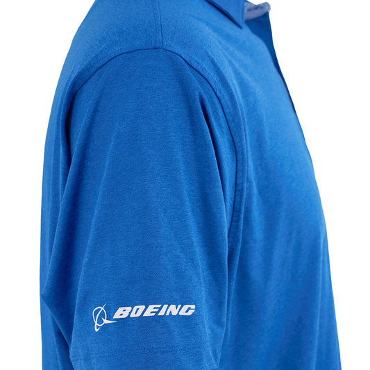 A close-up of a person wearing the Boeing 787 Dreamliner Series Men’s Polo by BOEING, featuring a blue moisture-wicking fabric, UPF 50 protection, and the white Boeing logo on the left sleeve. The image highlights texture and stitching.