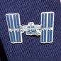 A close-up of the Boeing Illustrated ISS Lapel Pin by The Boeing Store shows a silver tone pin shaped like the International Space Station, with solar panels and modules in an epoxy finish, attached to dark navy textured fabric.