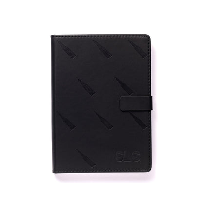 The elegant Boeing SLS Notebook by The Boeing Store boasts a sleek black leather cover adorned with vertical bottle-like patterns, an embossed SLS in the bottom right corner, and a convenient strap closure. Ready for your thoughts to soar, it is presented on a white background.