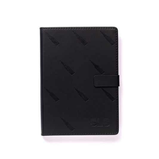 The elegant Boeing SLS Notebook by The Boeing Store boasts a sleek black leather cover adorned with vertical bottle-like patterns, an embossed SLS in the bottom right corner, and a convenient strap closure. Ready for your thoughts to soar, it is presented on a white background.